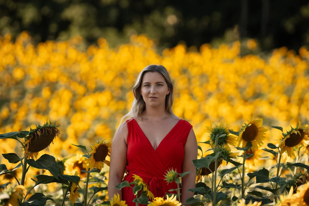 Frau mit rotem Jumpsuit im gelben Sonnenblumenfeld