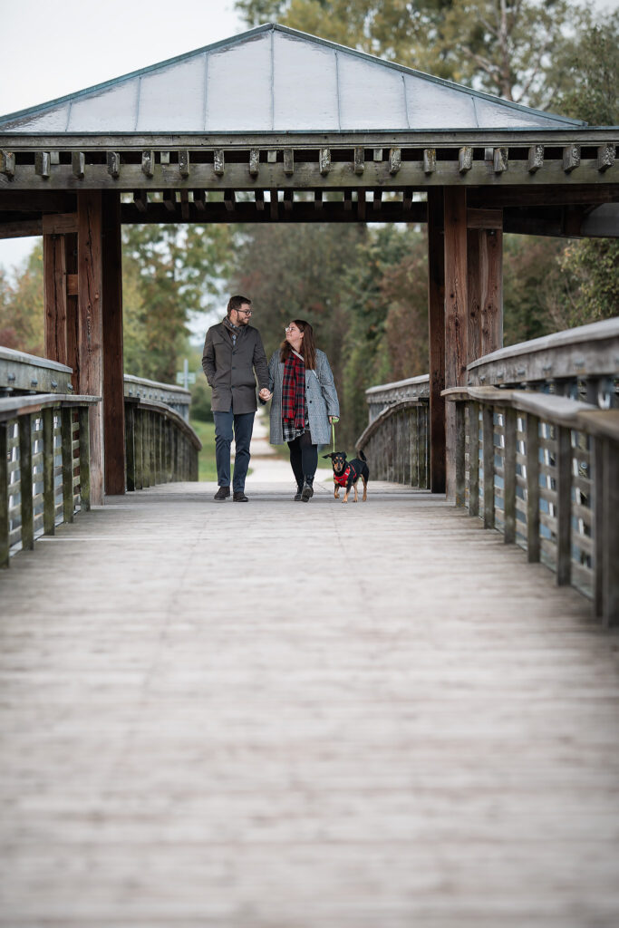 Paar geht gemeinsam mit Hund auf einer Brücke spazieren