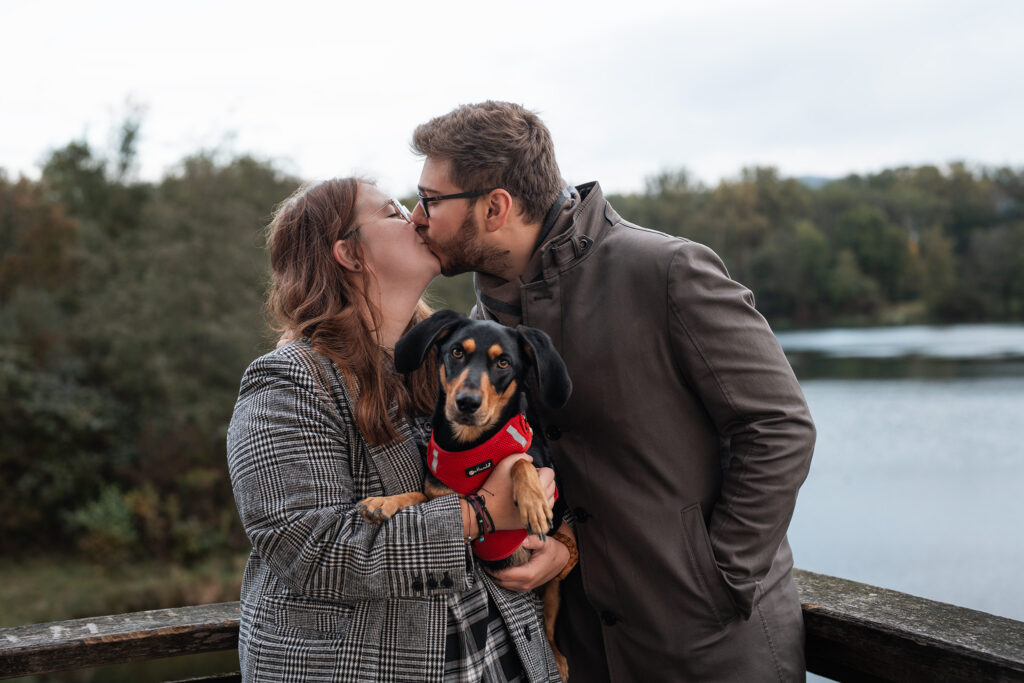 Pärchen küsst sich und hat Hund im Arm